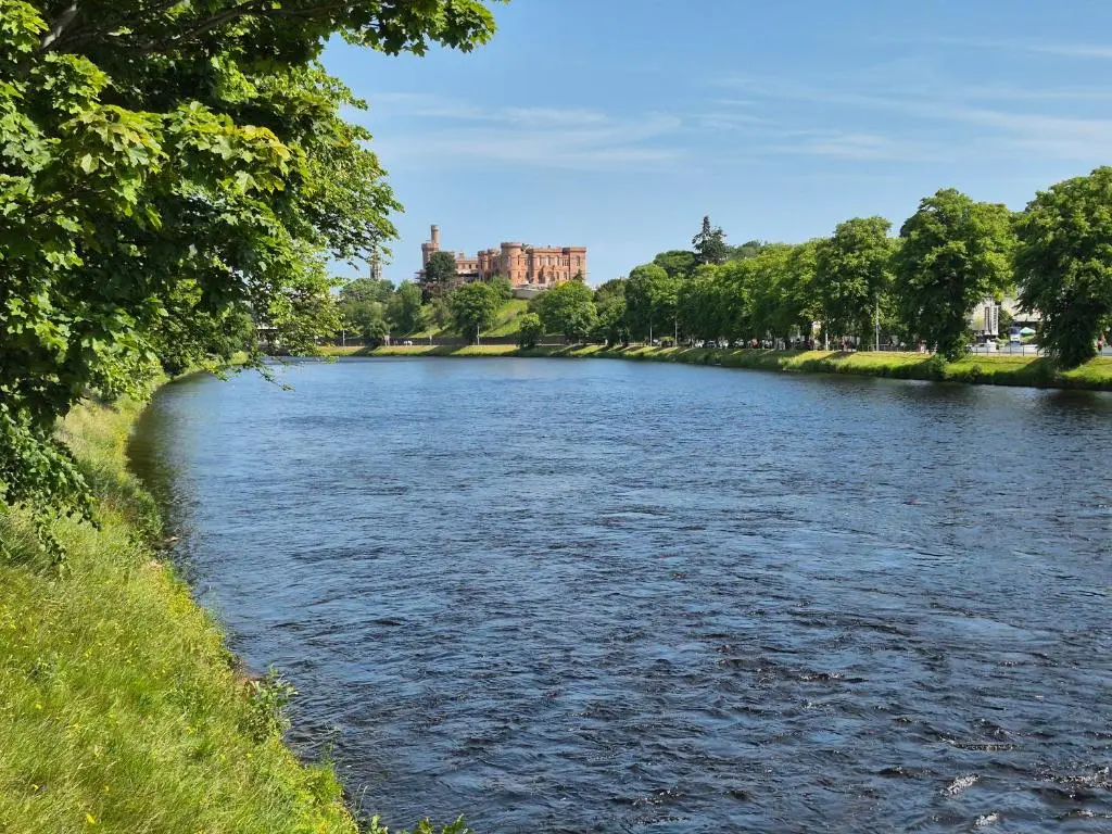 a river with a castle in the background at Riverside Gardens in Dalneigh