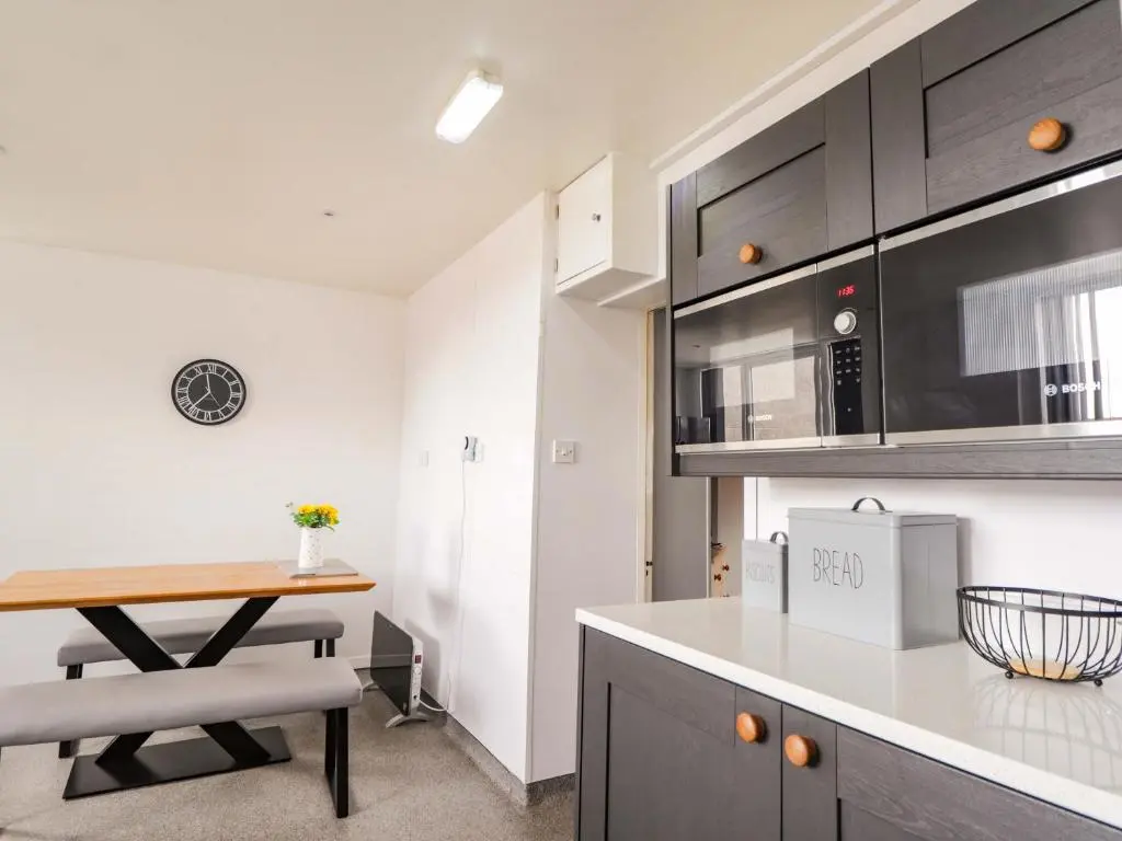 a kitchen with a wooden table and a counter top at Crannoch Self Catering in Buckie