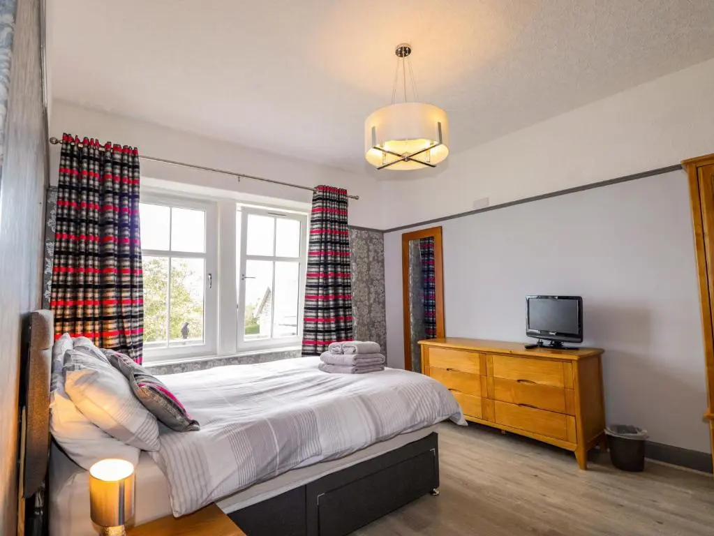 a bedroom with a bed and a tv and a window at Crannoch Self Catering in Buckie