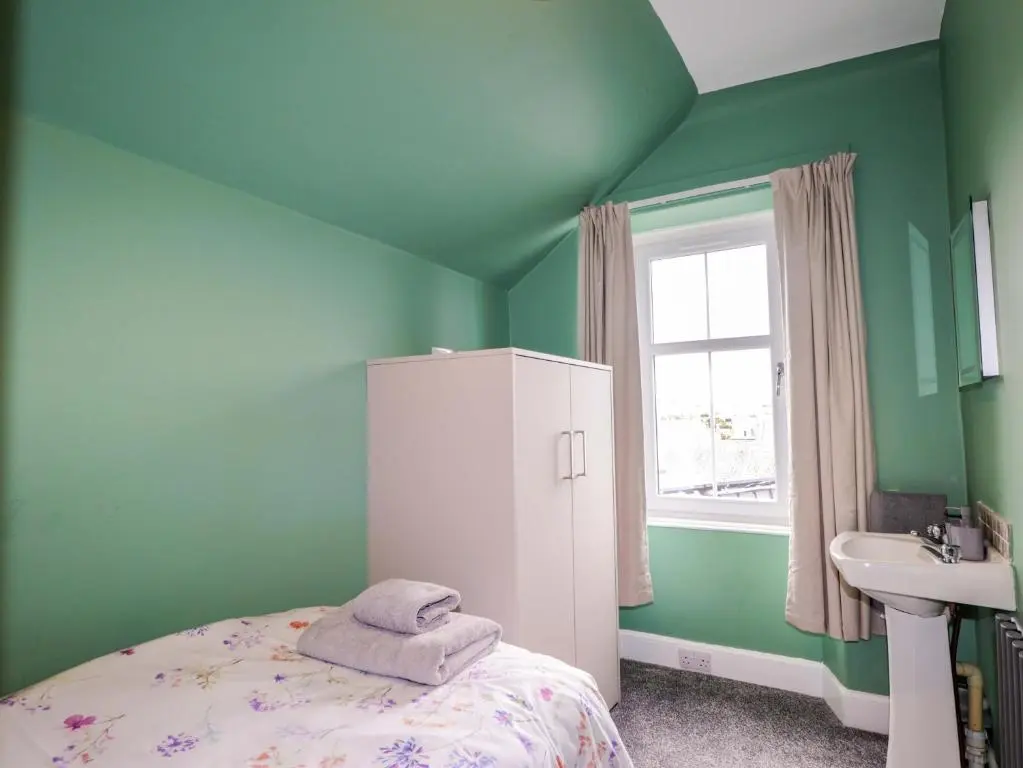 a green bedroom with a bed and a sink at Crannoch Self Catering in Buckie