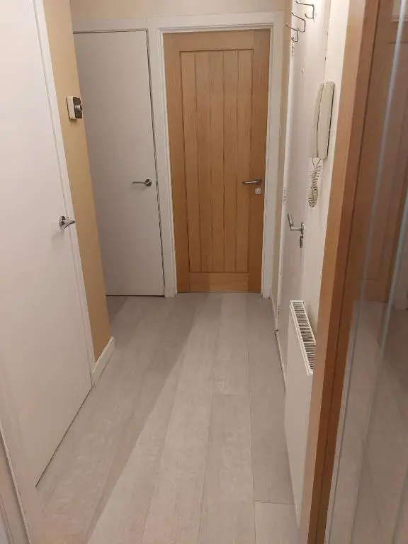 a hallway with a wooden door and a phone at Church Street Apartments in Inverness