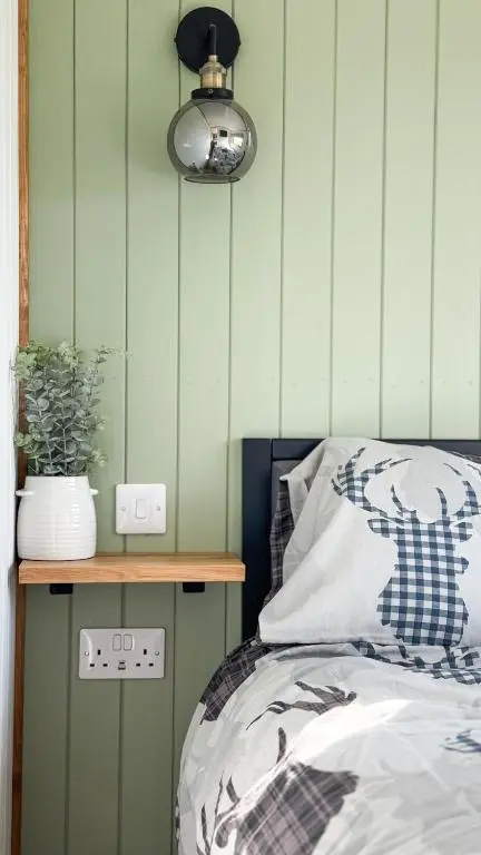 a bedroom with a bed and a nightstand with a plant at Cnocvann Croft Shepherd Huts in Kilmorack