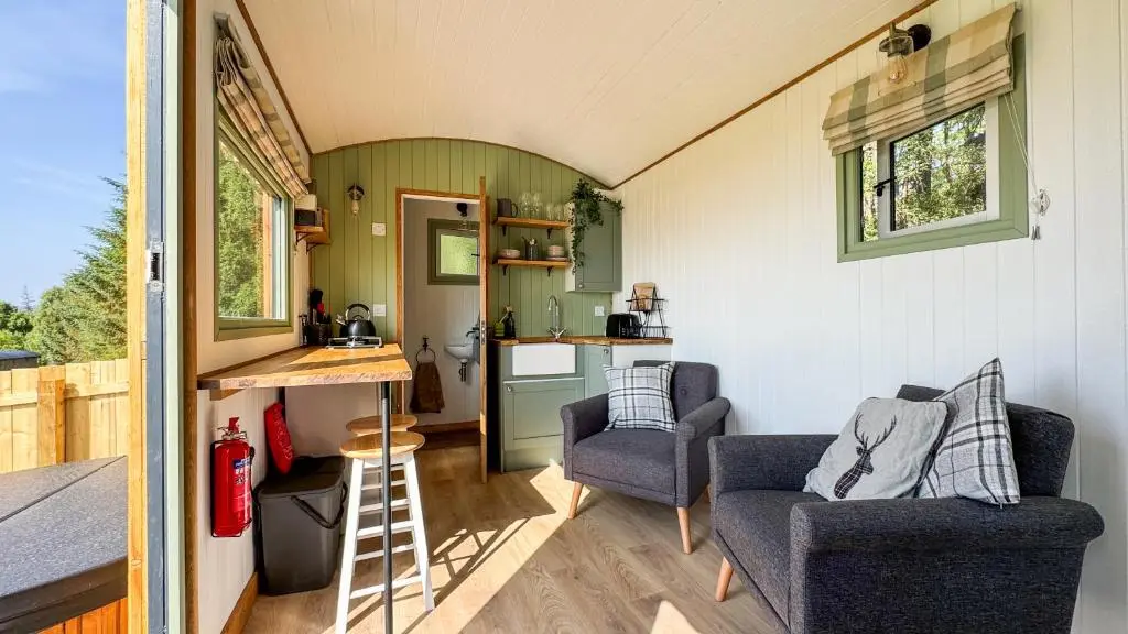 a tiny house with a kitchen and a living room at Cnocvann Croft Shepherd Huts in Kilmorack