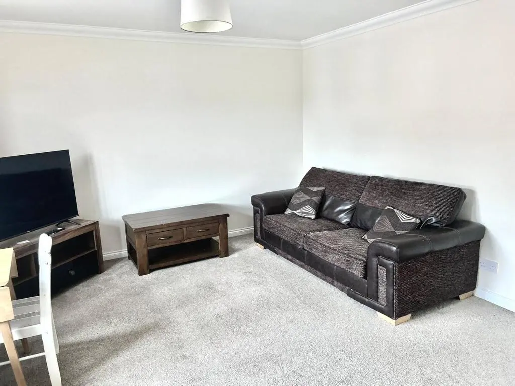 a living room with a black couch and a tv at Coz, 2Bed Central Elgin - Free parking, WiFi in Elgin