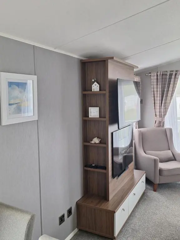 a living room with a television and a chair at Northern Lights in Lossiemouth