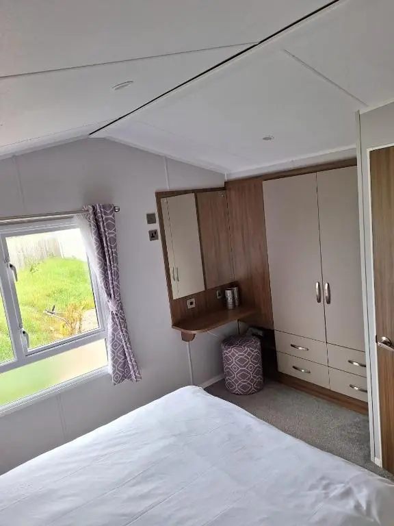 a bedroom with a white bed and a window at Northern Lights in Lossiemouth