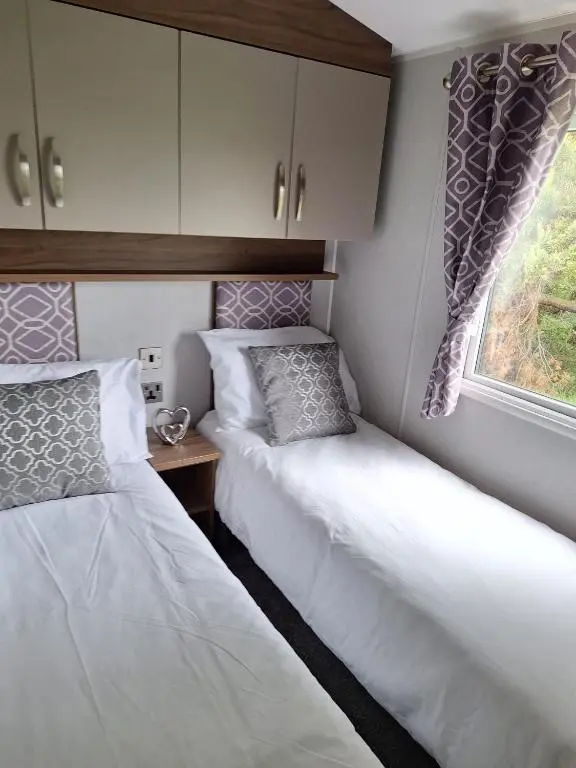 two beds in a small room with a window at Northern Lights in Lossiemouth
