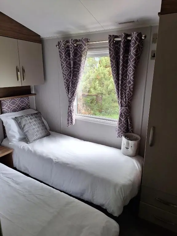 two beds in a small room with a window at Northern Lights in Lossiemouth