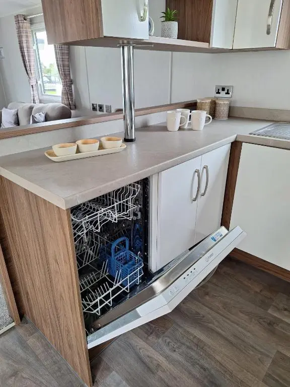 a kitchen with an open dishwasher in a counter at Northern Lights in Lossiemouth