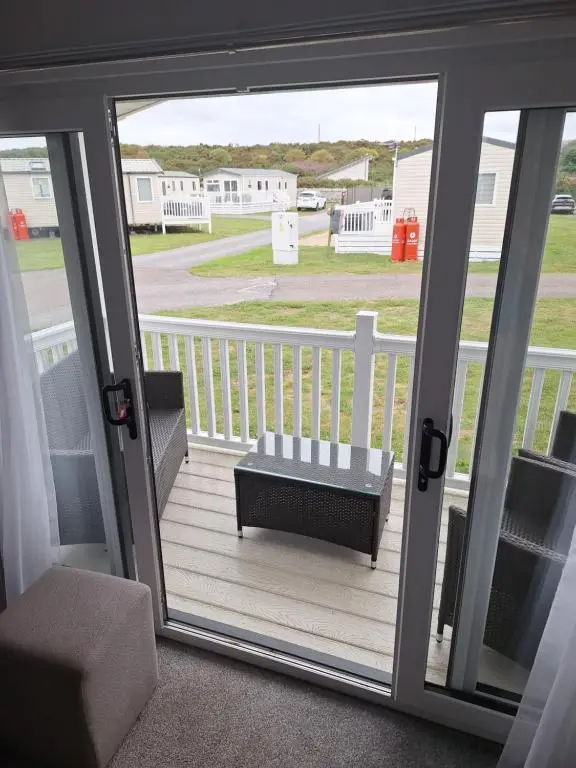 a sliding glass door with a bench on a porch at Northern Lights in Lossiemouth
