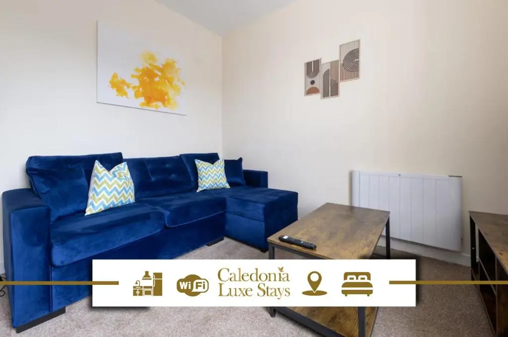 a living room with a blue couch and a table at Alba Apartment in Inverness