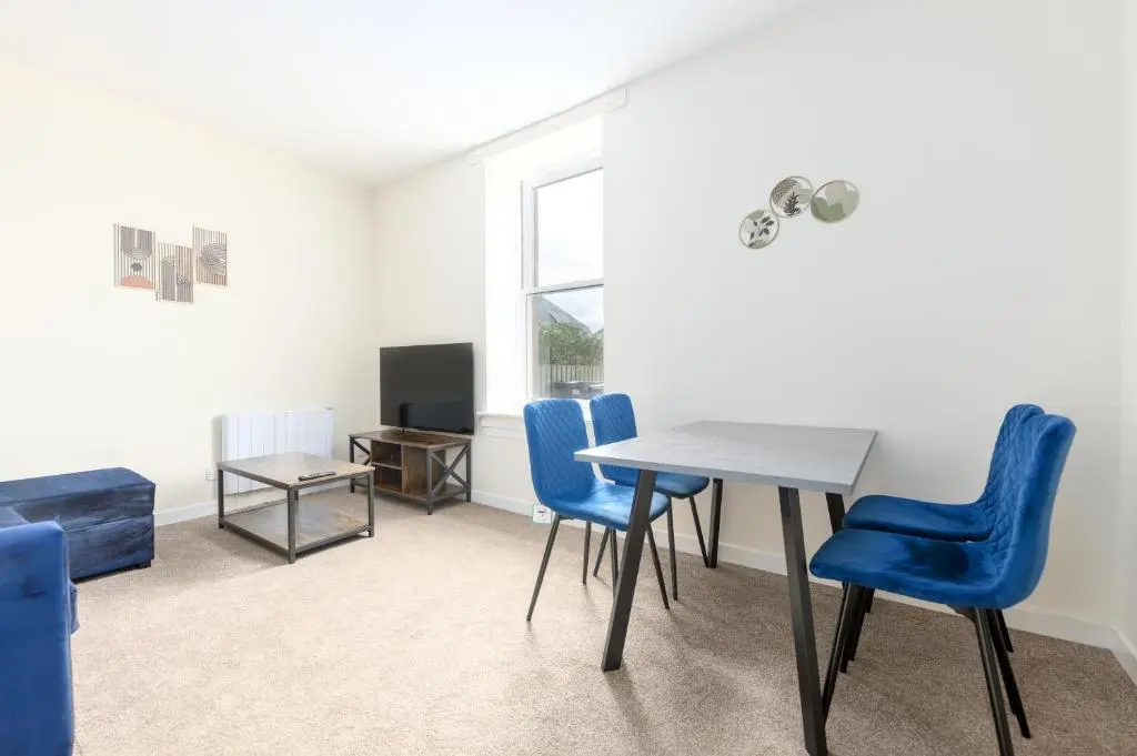 a dining room with blue chairs and a table at Alba Apartment in Inverness