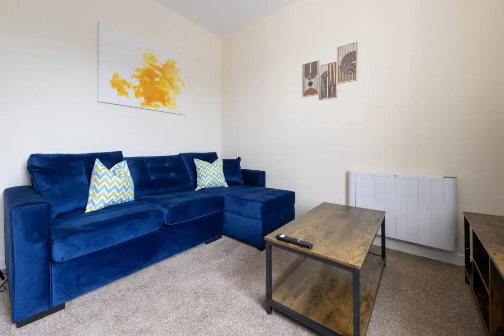 a blue couch in a living room with a table at Alba Apartment in Inverness