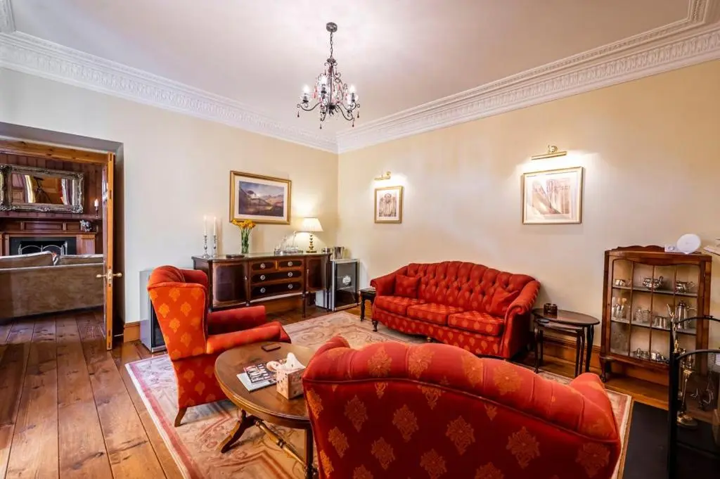 a living room with red furniture and a chandelier at Ross-shire Hall in Evanton