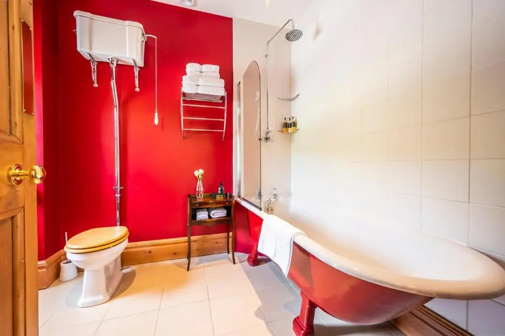 a red bathroom with a tub and a toilet at Ross-shire Hall in Evanton