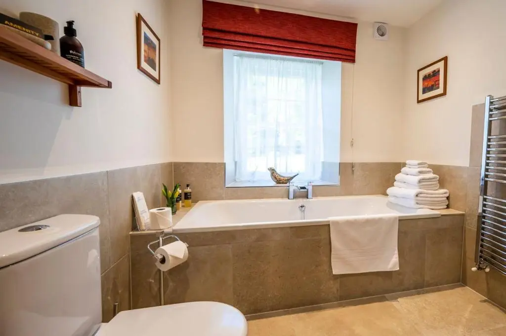 a bathroom with a tub and a toilet and a window at Ross-shire Hall in Evanton