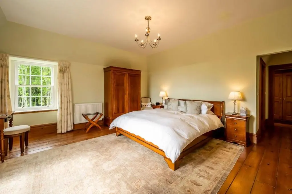 a bedroom with a large bed and a chandelier at Ross-shire Hall in Evanton