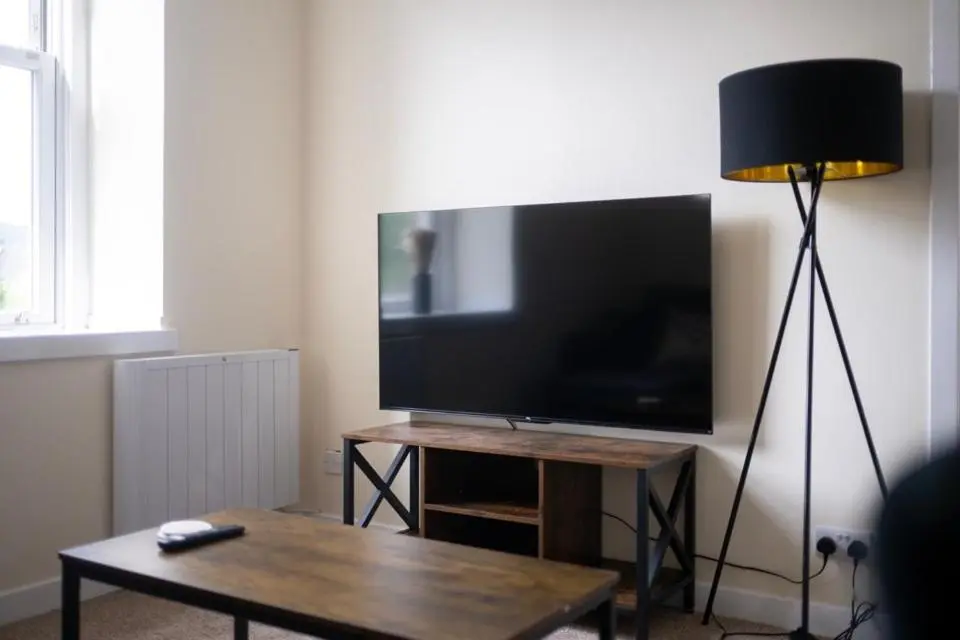 a living room with a flat screen tv and a table at 1 BDR Apt By Caledonia Luxe Stays Short Lets & Serviced Accommodation Inverness in Inverness