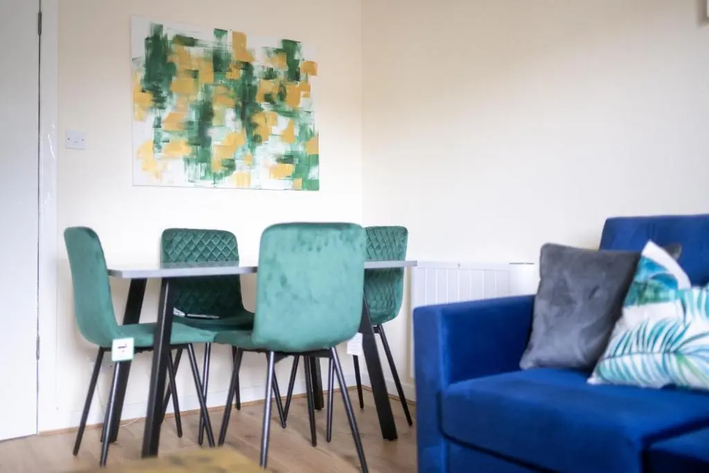 a table with four chairs and a blue couch at 1 BDR Flat At Caledonia Luxe Stays Short Lets & Serviced Accommodation Inverness in Inverness