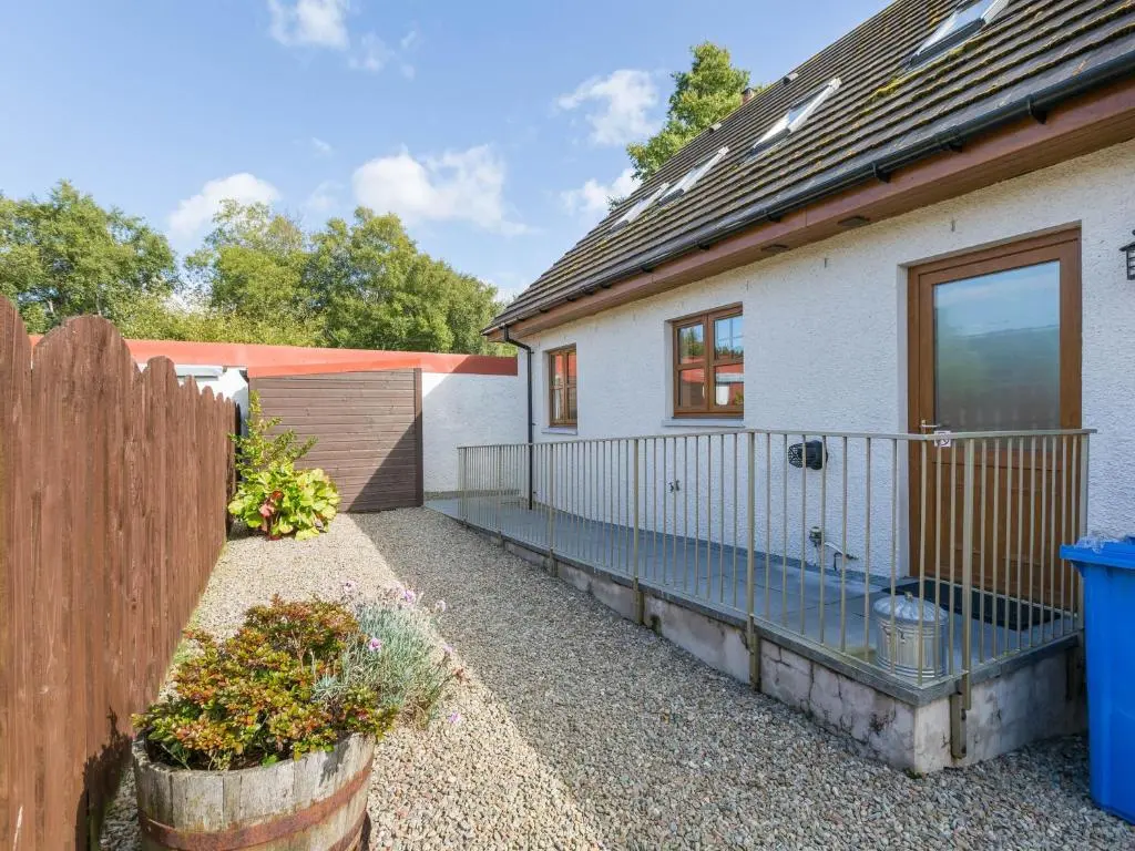 a house with a fence next to a yard at Broombank Cottage in Inverness