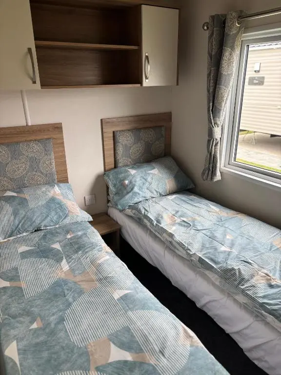 two beds in a small room with a window at Lighthouse View in Lossiemouth