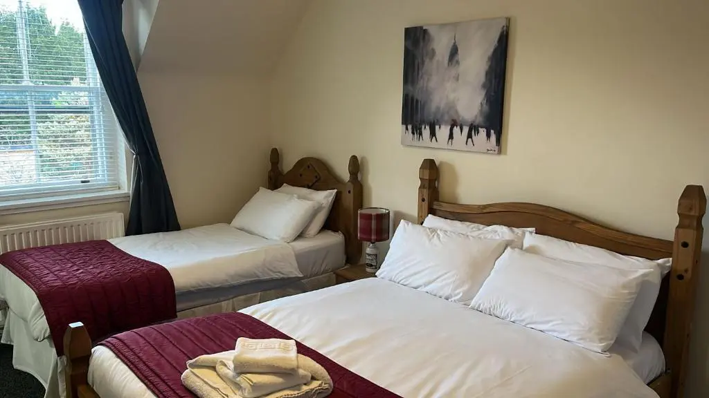 a hotel room with two beds and a window at Novar Arms Hotel in Evanton