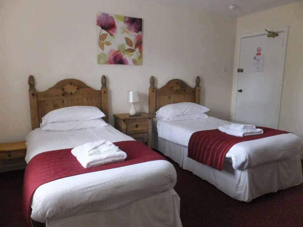 two beds in a hotel room with towels at Novar Arms Hotel in Evanton