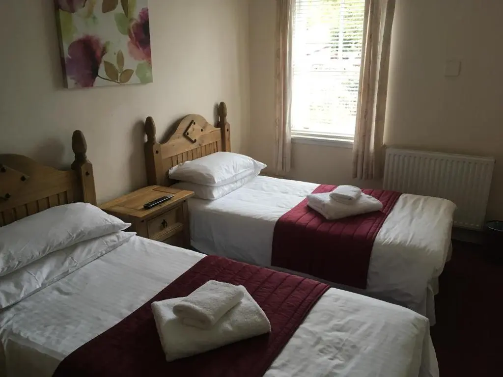 two beds in a room with towels on them at Novar Arms Hotel in Evanton