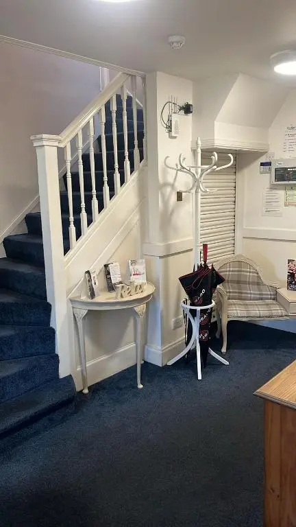 a room with a staircase and a table and a piano at Novar Arms Hotel in Evanton