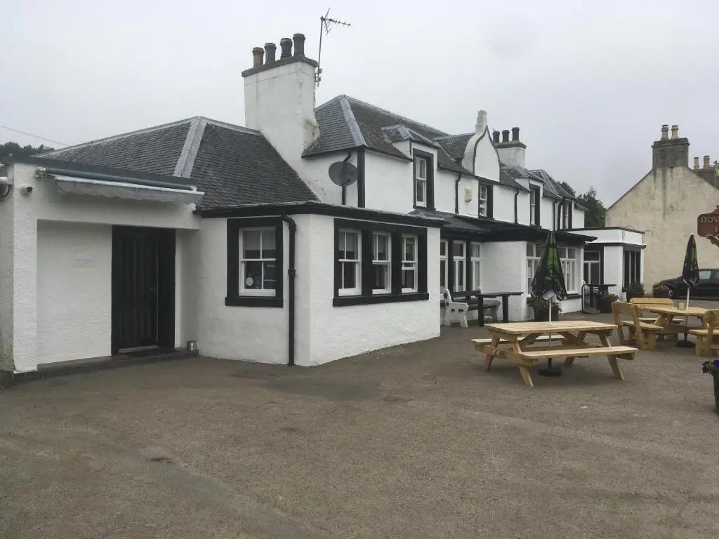 a building with a picnic table in front of it at Novar Arms Hotel in Evanton