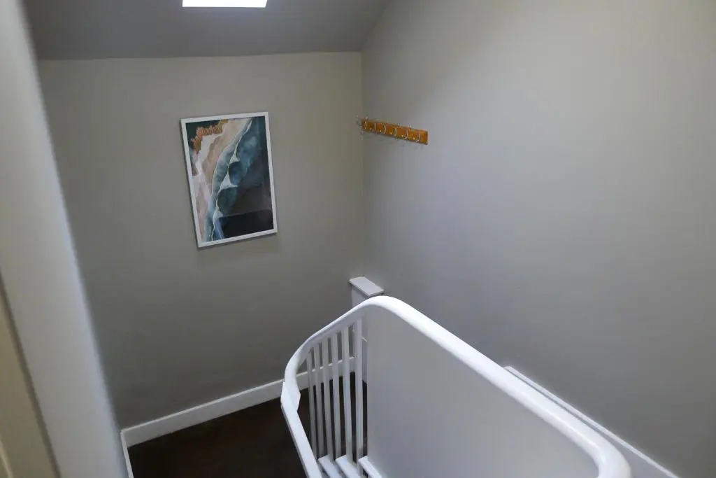 a staircase with a white rail and a painting on the wall at Hanover st partment in Fraserburgh