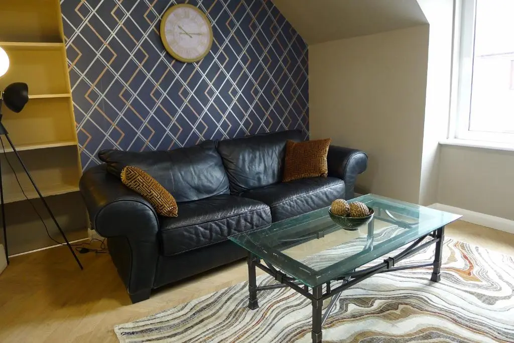 a living room with a leather couch and a glass table at Hanover st partment in Fraserburgh