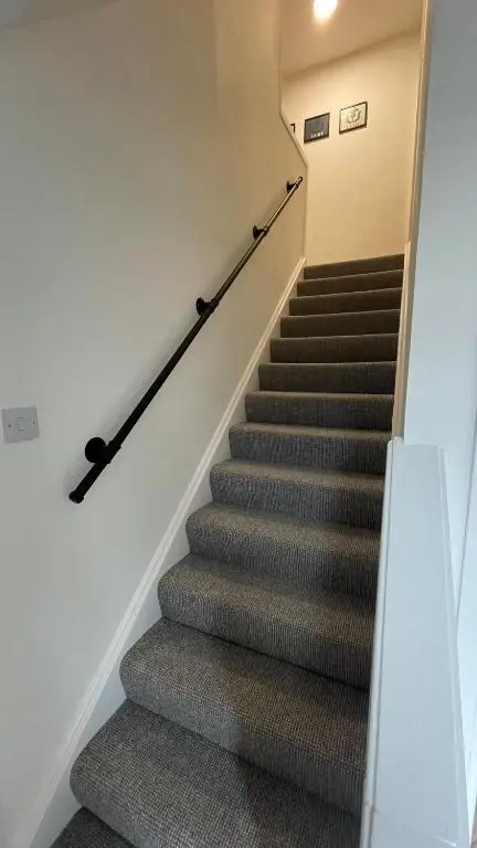 a staircase in a house with grey carpet at The Den - by Caithness Luxury Apartments NC500 - 2 Bedroom holiday home - Sleeps Work teams upto 2 & holiday makers upto 4 in Wick