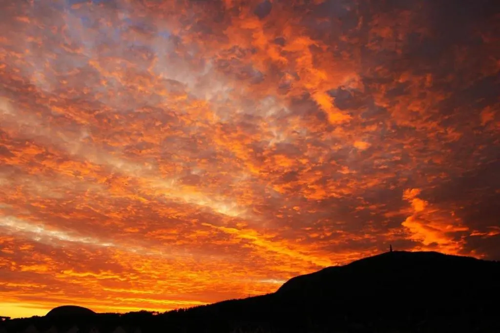 a sunset with a person standing on top of a hill at Migdale Heights - Luxury Cabins in The Highlands in Bonar Bridge