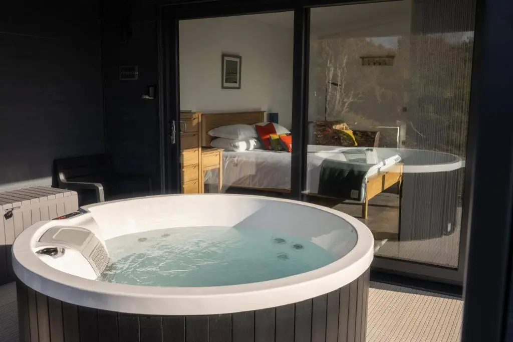 a hot tub in a room with a bedroom at Migdale Heights - Luxury Cabins in The Highlands in Bonar Bridge