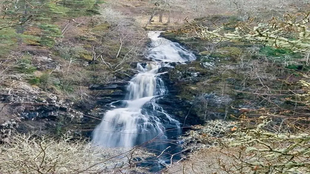 an aerial view of a waterfall in a forest at Dhivach Lodge in Drumnadrochit