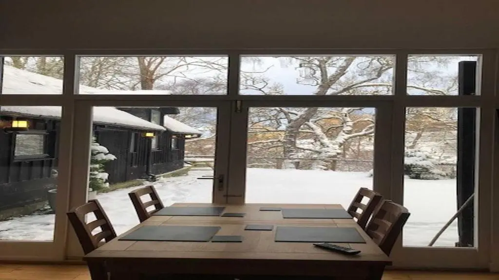 a dining room table with a view of a snow covered yard at Coach House in Drumnadrochit