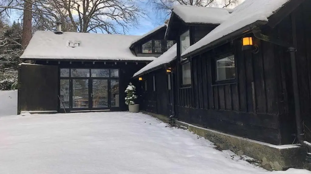 a black house with snow on the roof at Coach House in Drumnadrochit
