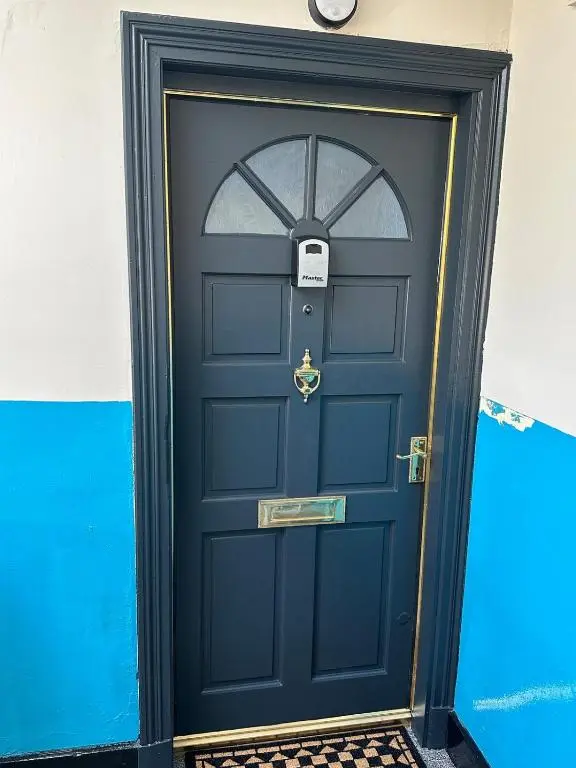 a navy blue door with a clock on top at Highland Home on the Hill in Inverness