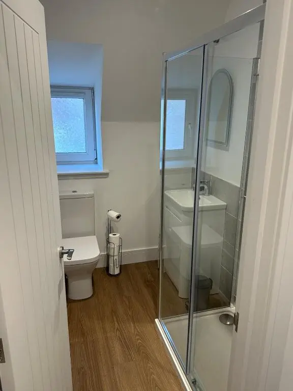 a bathroom with a toilet and a glass shower at Highland Home on the Hill in Inverness