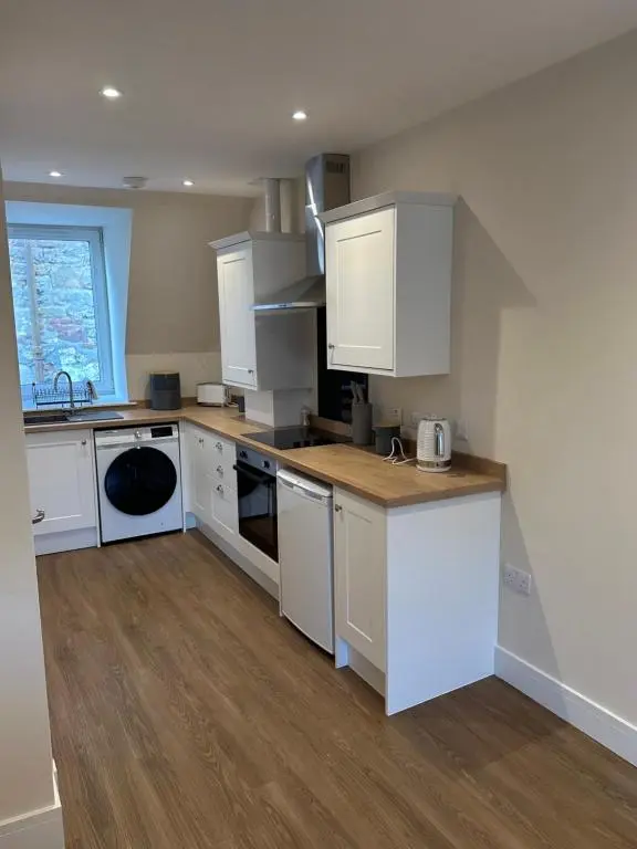 a kitchen with white cabinets and a wooden floor at Highland Home on the Hill in Inverness