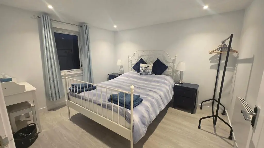 a bedroom with a bed with a blue and white comforter at Charlies Cottage in Inverness