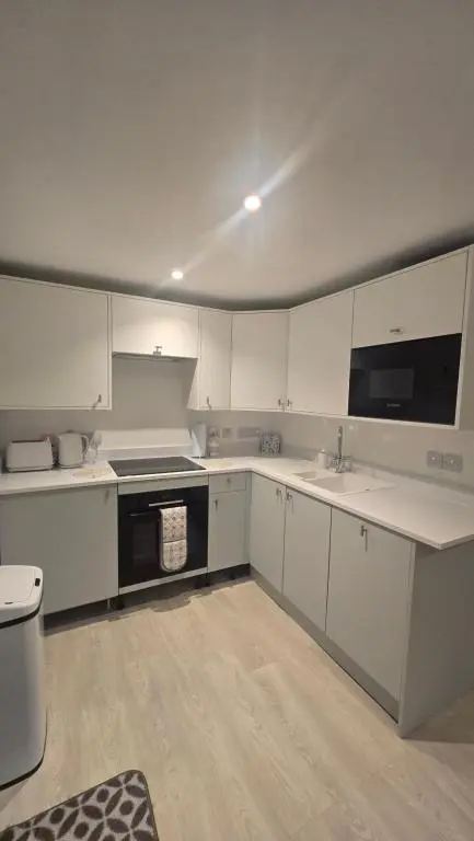 a kitchen with white cabinets and a stove top oven at Charlies Cottage in Inverness