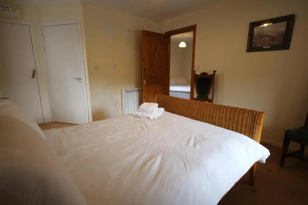 a bedroom with a large bed with white sheets at Woodlands Rest in Garve