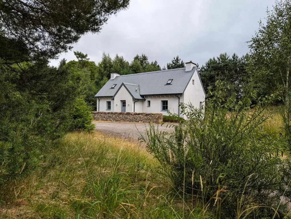 a white house with a gray roof on a road at Logies Croft in Kellas