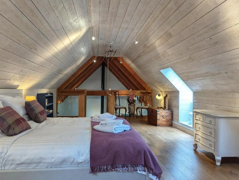 a bedroom with a large bed and a wooden ceiling at Logies Croft in Kellas
