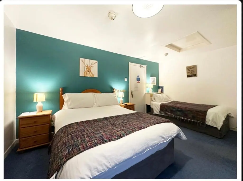 a bedroom with two beds and a blue wall at The Castle Hotel NR TAIN in Portmahomack