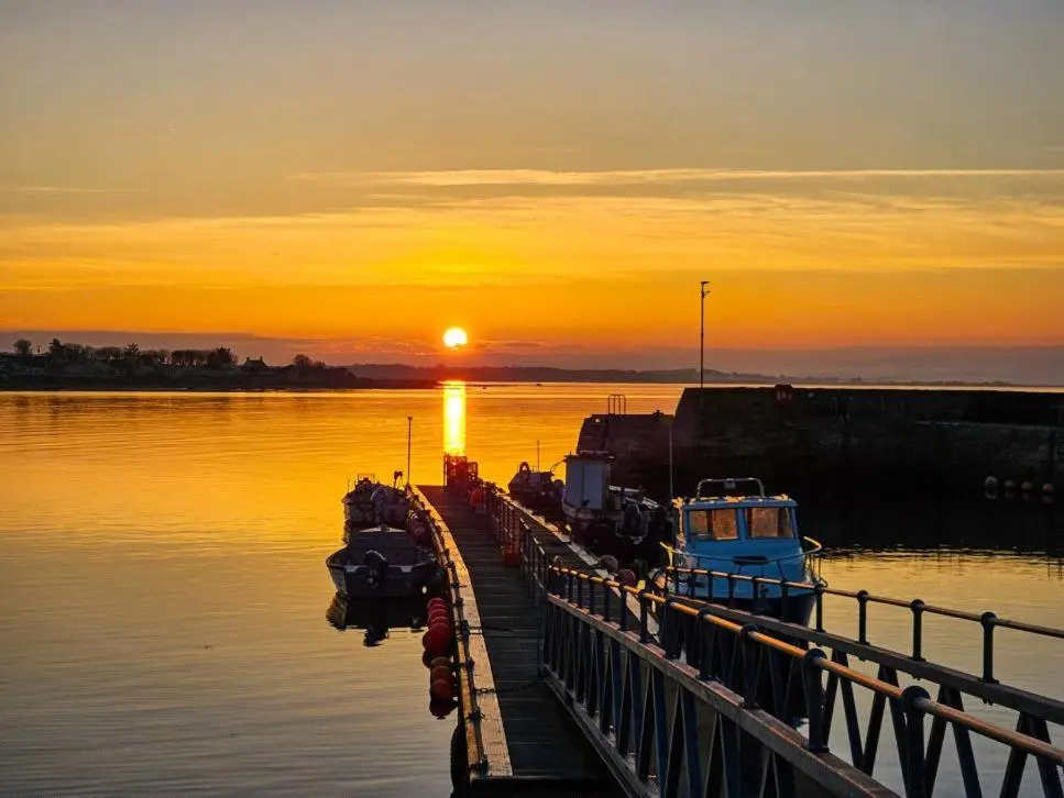 a dock with boats in the water at sunset at The Castle Hotel NR TAIN in Portmahomack