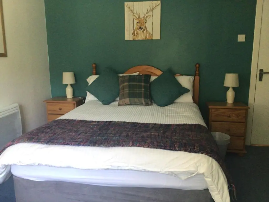 a bedroom with a large bed with green walls at The Castle Hotel NR TAIN in Portmahomack