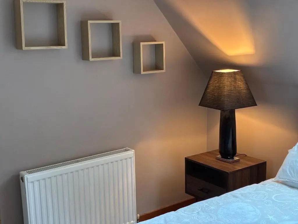 a lamp on a night stand next to a bed at Cottage Farmhouse in Huntly